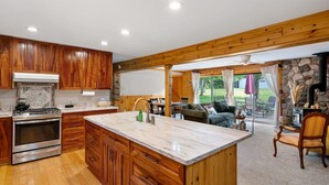 Une cuisine spacieuse avec des meubles en bois, un grand îlot central et une cheminée en pierre.