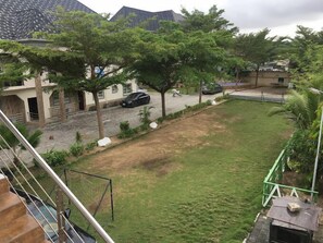 A residential area with a grassy lawn, trees, and a street with parked cars. - Amsterdam Court Residence (Lekki)