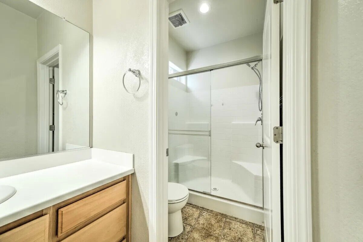 Un baño con tocador blanco, cabina de ducha de vidrio y un inodoro.