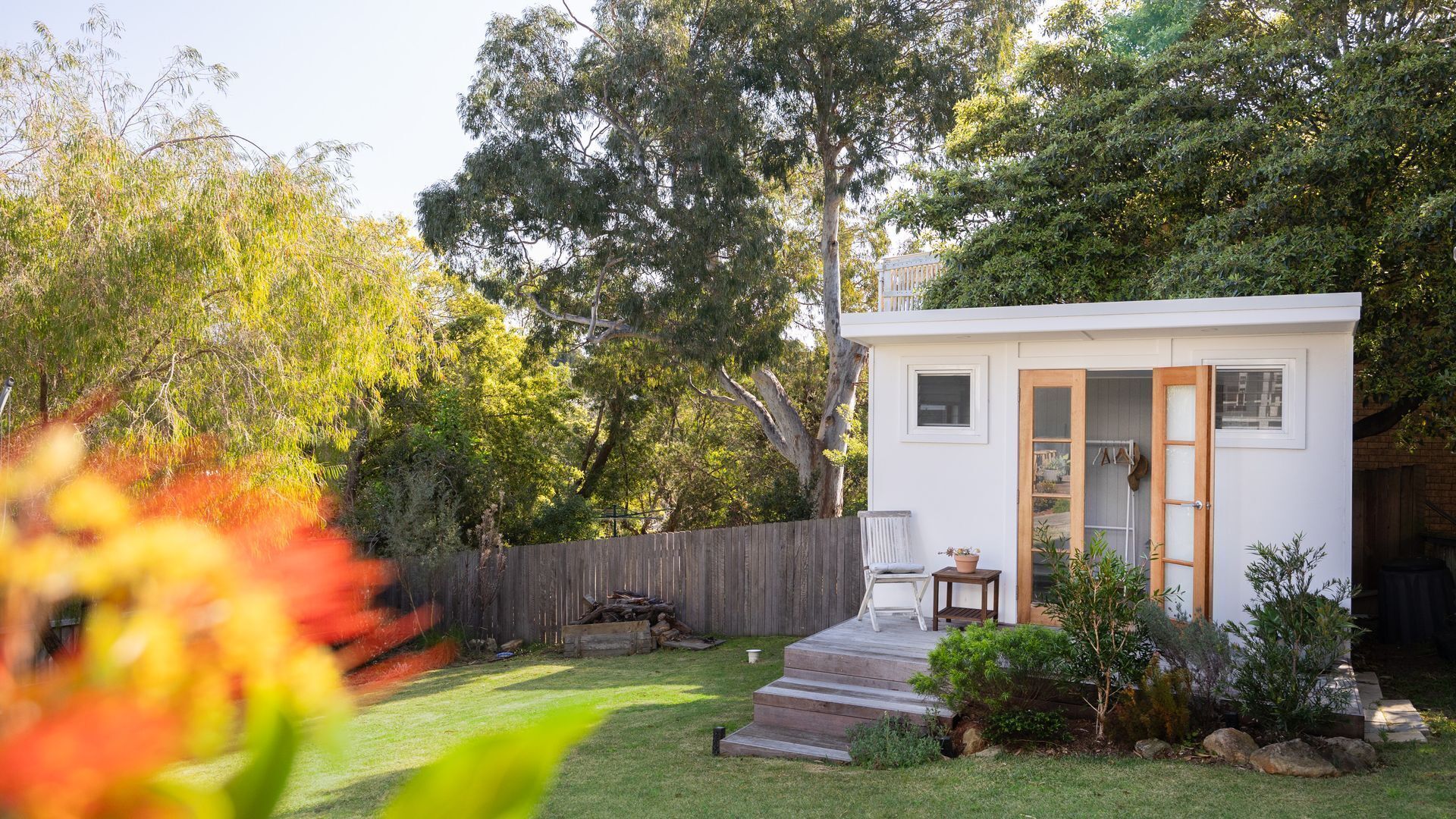 A small, single-story house with a wooden deck, a front door, and a small porch area.