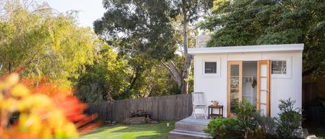 A small, single-story house with a wooden deck, a front door, and a small porch area.
