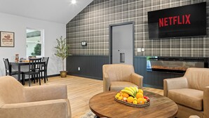 Moderni olohuone, jossa on ruokailutila, televisio, jolta näkyy Netflix, ja keittiö.