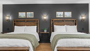 A room with two beds, wooden headboards, a small bedside table with a plant, and wall-mounted light fixtures.