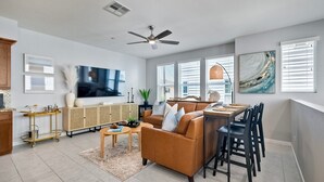 Una sala de estar moderna con sofá, televisor y comedor.