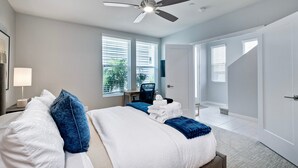 Una habitación de hotel moderna con cama, escritorio y ventilador de techo.