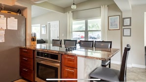 Una cocina con encimera de granito, electrodomésticos de acero inoxidable y una zona de comedor con sillas y una mesa.