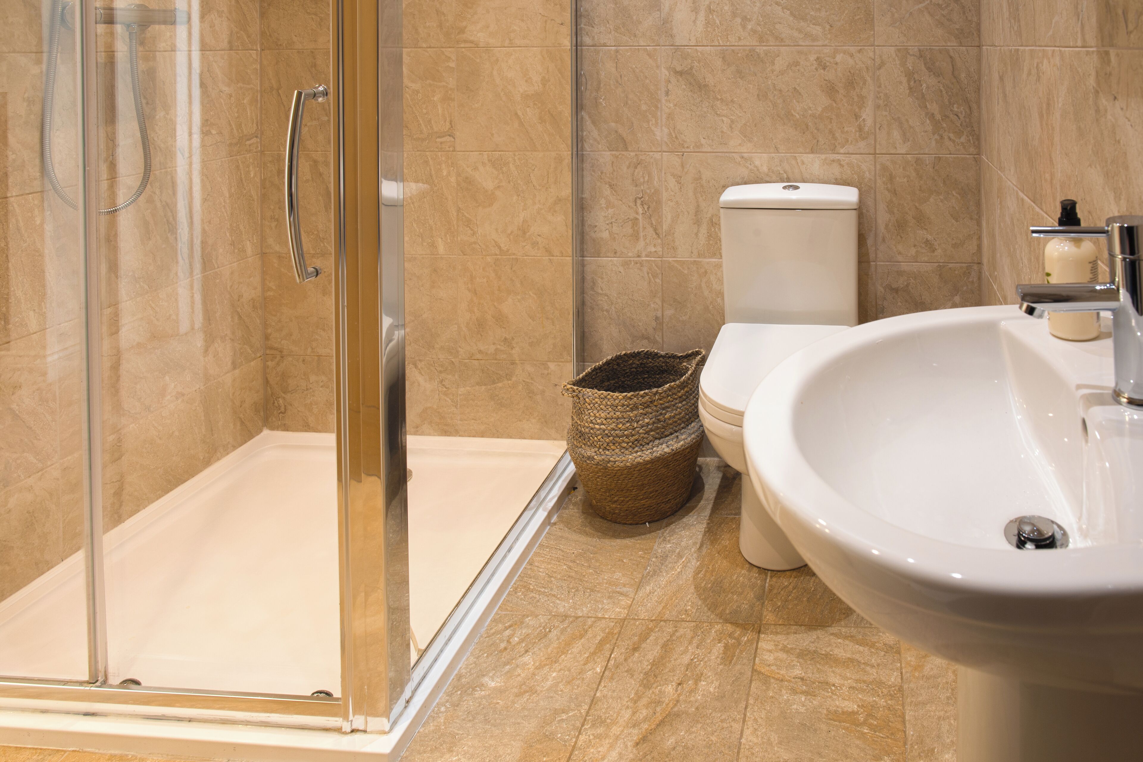 Ein modernes Badezimmer mit einer Glaskabine zur Dusche, einer weißen Toilette und einem Waschbecken mit Spiegel.