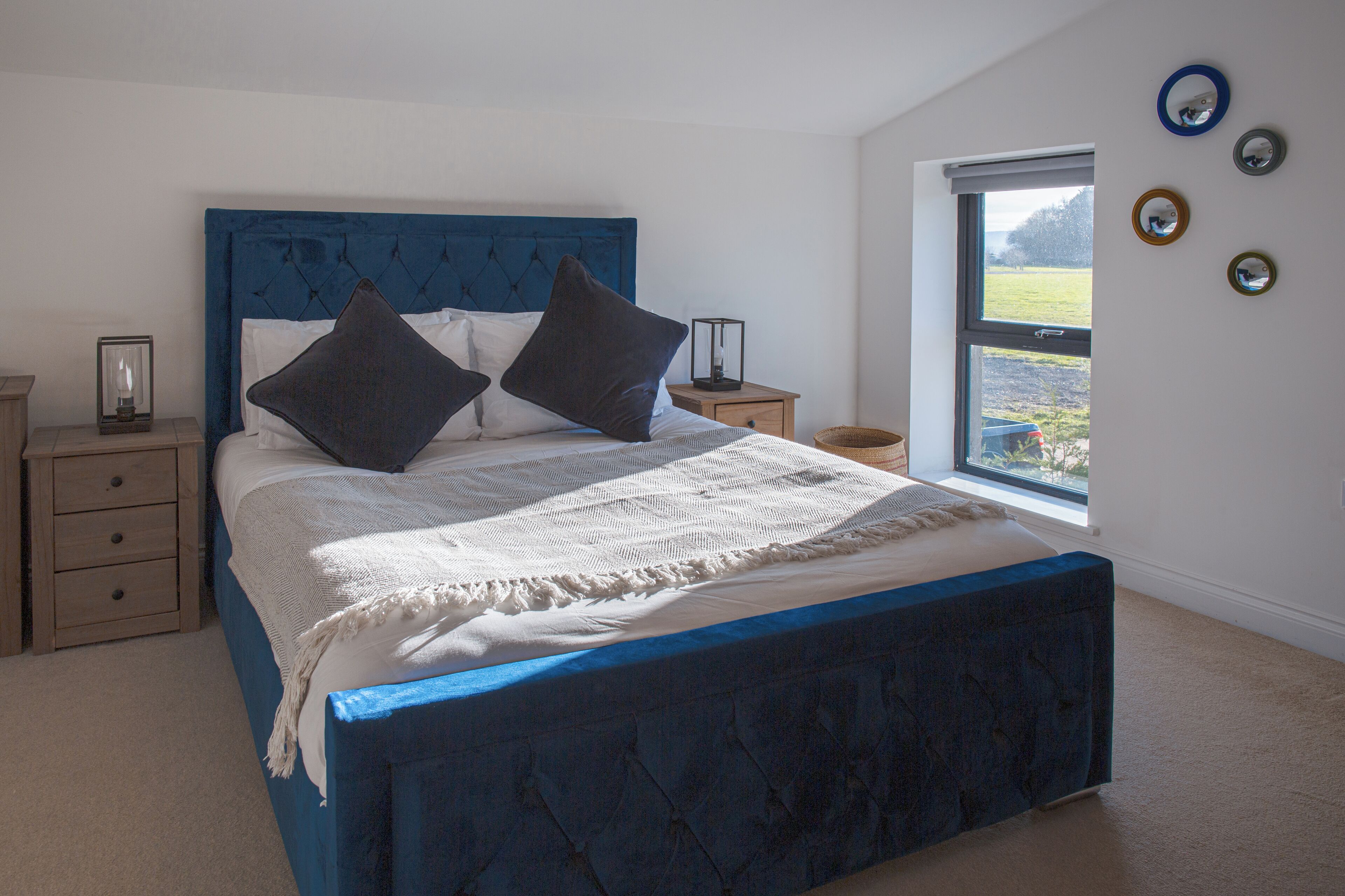 Een slaapkamer met een groot bed, een nachtkastje, een raam met uitzicht en decoraties aan de muur.