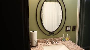 A bathroom with a large oval mirror, a sink, and toiletries.