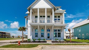 A two-story house with a balcony, a front porch, and a garage. - Foosball Table, Resort Pools, Golf Cart Boardwalk to the Beach, Pet Friendly (Port Aransas)