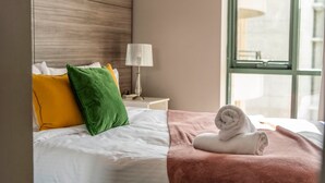 Une chambre d’hôtel avec un lit, des oreillers, une lampe et une fenêtre.