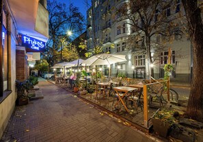 An outdoor café with tables and chairs, surrounded by trees and buildings. - Hoża 62 Deluxe Studio (Warszawa)