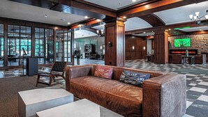 A lobby with a brown leather sofa, two white side tables, and a stone fireplace.