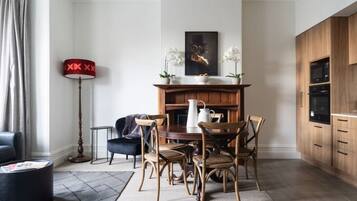 A dining area with a wooden table and chairs, a fireplace, and a modern kitchen with wooden cabinets.