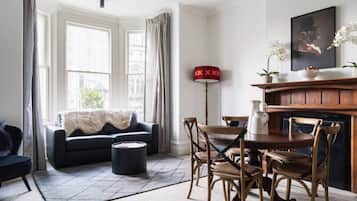 A living room with a dark sofa, wooden chairs, a coffee table, and a fireplace.