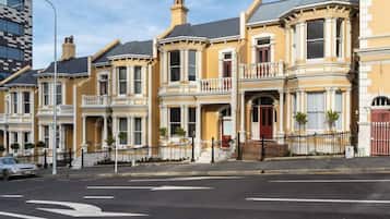 A row of Victorian-style townhouses with bay windows, a gated driveway, and a street view.