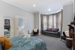 Une chambre avec un grand lit, un canapé, un fauteuil et un piano.