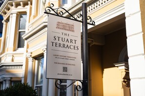 A sign for The Stuart Terraces, a luxury heritage townhouse with a classic architectural style, located at 199-219 Stuart Street, Dunedin.