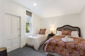 Une chambre avec deux lits simples, un grand lit, une fenêtre avec vue et une porte.