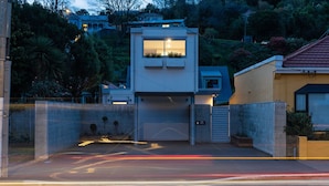 Ein modernes Haus mit Garage, umgeben von einer Hecke und Grünpflanzen.