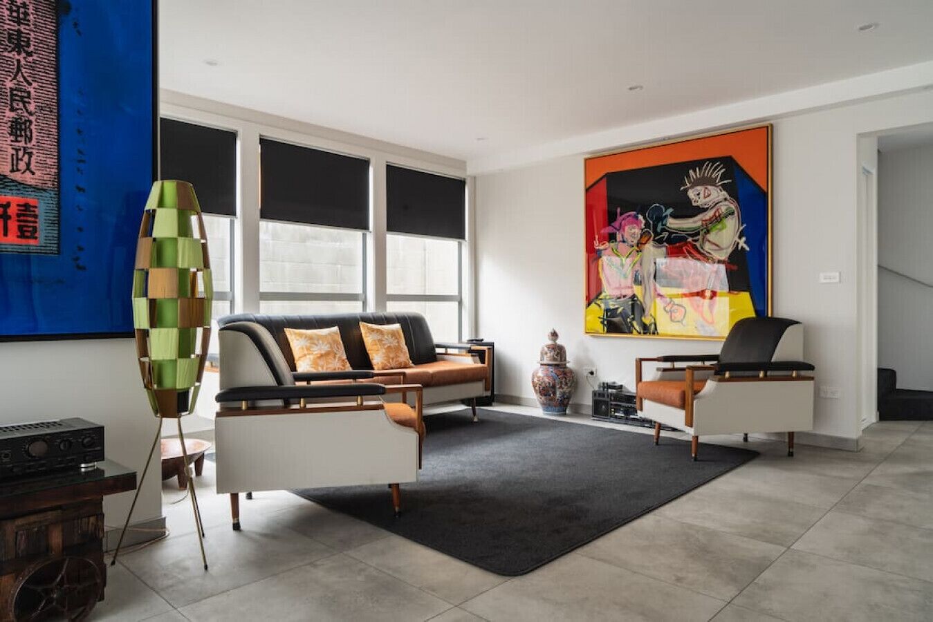 Un salon moderne avec un canapé, une table basse et un tapis. Il y a une grande fenêtre et un tableau au mur.