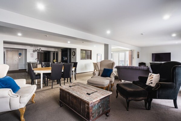 A spacious living area with a dining table, multiple chairs, a coffee table, and a sofa.