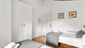 Una camera da letto con due letti, un armadio, un termosifone e due quadri appesi al muro.