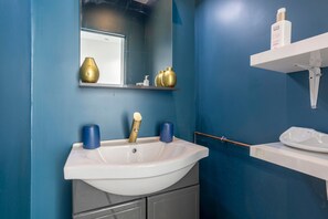 A bathroom with a white sink, a mirror, and a blue wall.