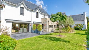 A modern house with a garage, a stone facade, and a well-maintained lawn.