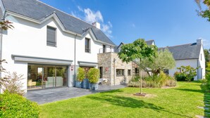 A modern two-story house with a garage, a stone facade, and a well-maintained lawn. - Holiday Home 'Villa Ker Minet - Maison 8 Pers' with Private Terrace, Wi-Fi and Air Conditioning (Piriac-sur-Mer)