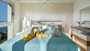 Una habitación de hotel con cama, candelabro, mesita de noche y vistas al exterior.