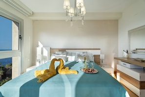 Una habitación de hotel con cama, candelabro, mesita de noche y vistas al exterior.