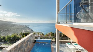 Una piscina con vista al océano, un edificio rojo y un cielo despejado.