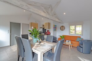 A modern living space with a dining area, kitchen, and seating area.