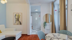 Een moderne woonkamer met een witte bank, een blauwe fauteuil, een marmeren tafel en een grote spiegel.