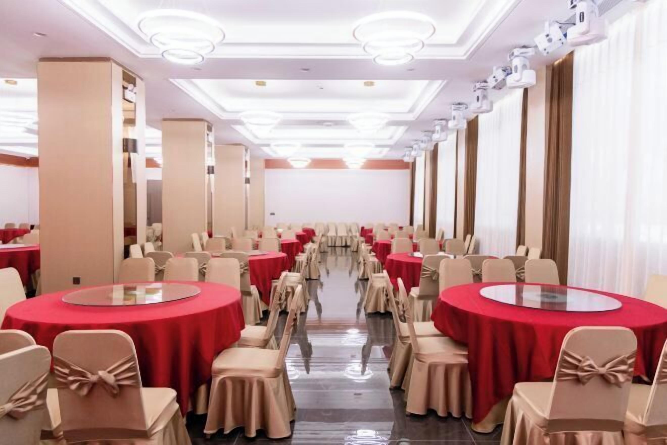 Un salón de banquetes con mesas redondas, sillas y un pasillo central.