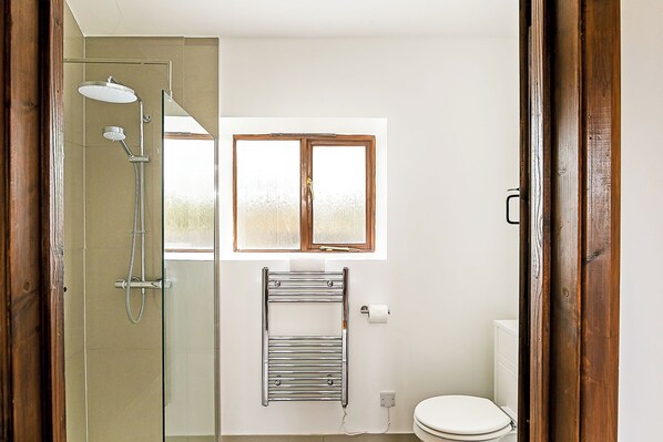A bathroom with a glass-enclosed shower, a towel rack, a window, and a toilet. - Glyme Flat Peaceful Country Retreat (Chipping Norton)