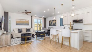 Une cuisine moderne avec des meubles blancs, un îlot central et des luminaires suspendus.