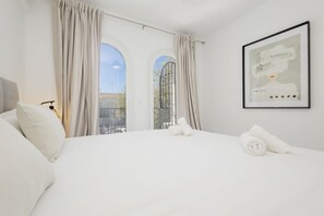 Relax in a serene space with a large bed and floor-to-ceiling windows.