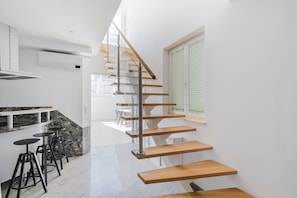 Staircase leads to an upper level from this modern kitchen with a stove and marble countertop.