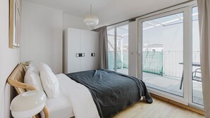 Quarto moderno com uma cama grande, guarda-roupa e porta de vidro deslizante para uma varanda.