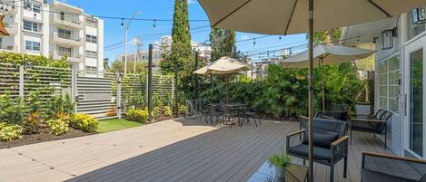 A wooden deck with outdoor furniture, a pergola with a canopy, and a view of a residential building.