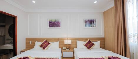 Une chambre d’hôtel avec deux lits, une tête de lit en bois, une table de chevet avec une lampe et des œuvres d’art accrochées aux murs.