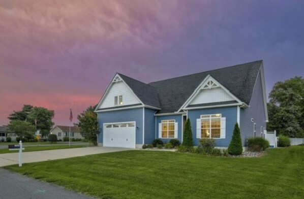 A two-story house with a dark roof, white trim, and a garage. - Spacious Coastal Home! Large game room, private pool, 5 minutes to beach! (Lewes)
