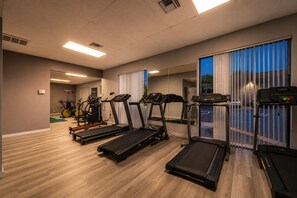 A gym with treadmills, stationary bikes, and a mirror.