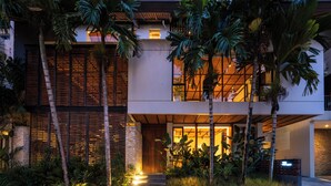 A modern two-story house with a stone facade, large windows, and a well-lit entrance.