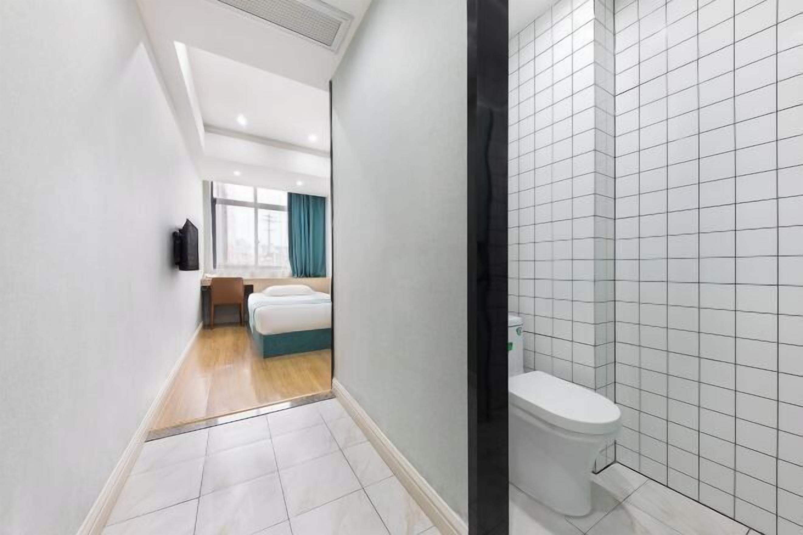 A modern bathroom with white tiles, a toilet, and a shower area.