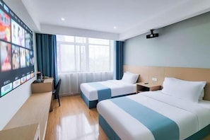 A hotel room with two beds, a desk, a chair, a TV mounted on the wall, and a window with curtains.
