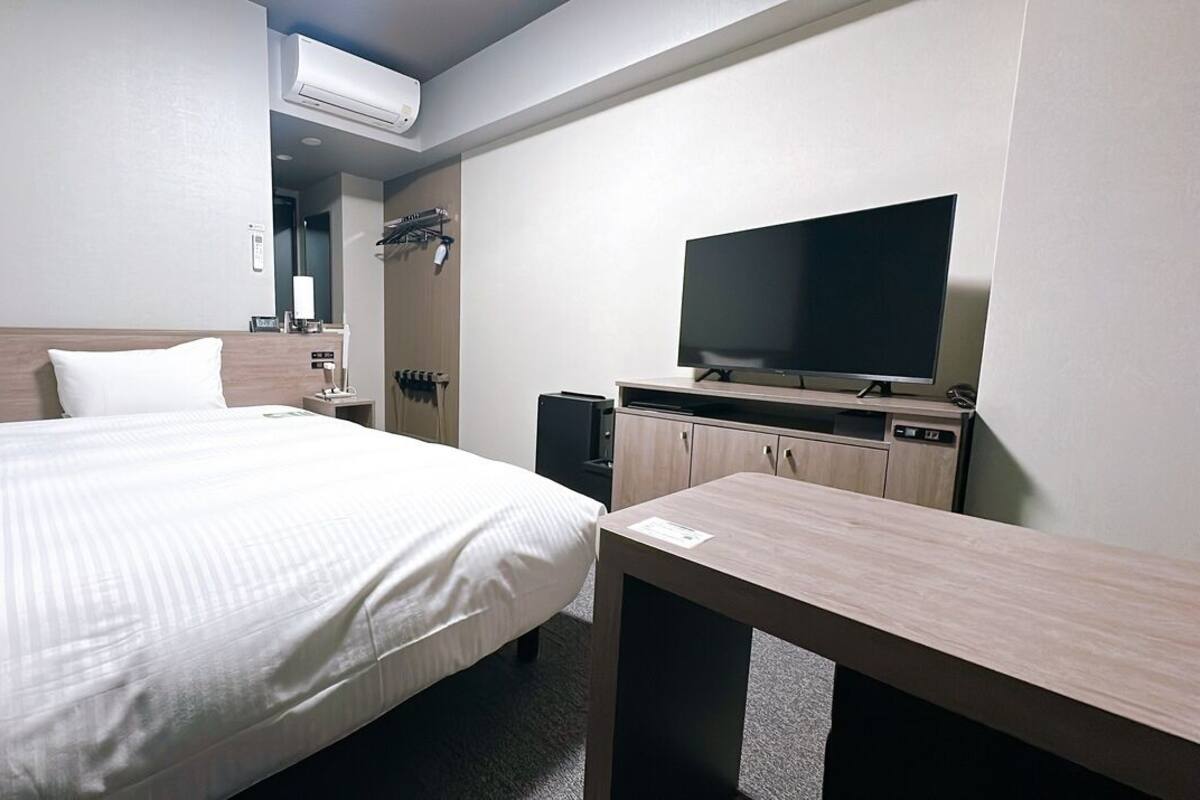 A hotel room with a bed, a TV, a desk, and a wardrobe.