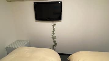 Una camera d'albergo con due letti, una TV a schermo piatto, un condizionatore d'aria e un tavolino.
